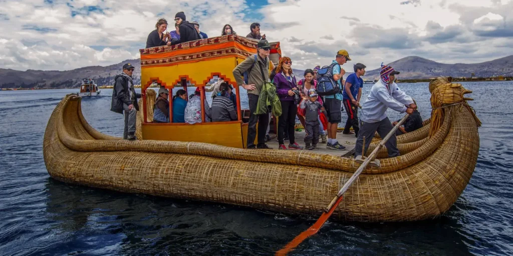Turistas extranjeros navegando en una balsa tradicional de totora en el Lago Titicaca